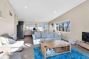 a living room with a couch and a table at Fun on the Fairway in Matarangi