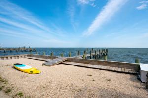 a yellow surfboard on the beach next to a pier at Serenity Now in Greenbackville