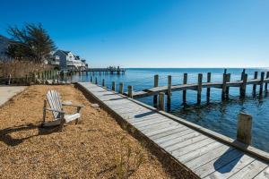 a bench sitting on the beach next to a dock at Serenity Now in Greenbackville +45 photos