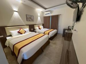 a hotel room with two beds and a television at Marina Cua Lo Hotel in Cửa Lô