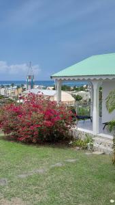 a gazebo with a bench and pink flowers at Bungalow vue sur mer in Sainte-Anne
