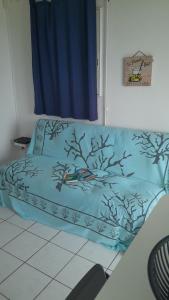 a couch in a living room with a blue blanket at Bungalow vue sur mer in Sainte-Anne