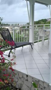 a porch with a bench and flowers on a balcony at Bungalow vue sur mer in Sainte-Anne +6 photos