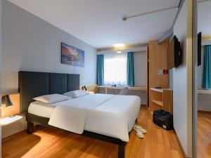 a bedroom with a large white bed and a bathroom at ibis Köln Frechen in Cologne
