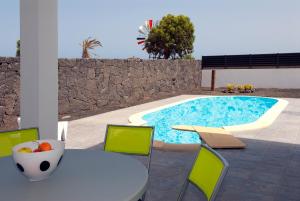 un patio con mesa, sillas y piscina en Villas Las Maretas, en Costa Teguise