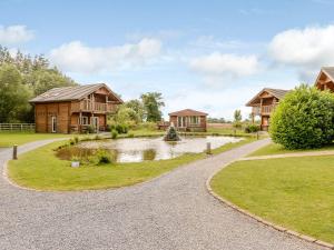 a house with a pond in front of a house at Pine Lodge Spa Pet in Thirsk