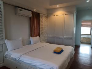 a bedroom with a white bed with a yellow towel on it at jomtien 5BR villa in Pattaya South