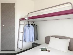 a bedroom with a bunk bed with a shirt on a ladder at ibis budget Berlin Hoppegarten in Hoppegarten