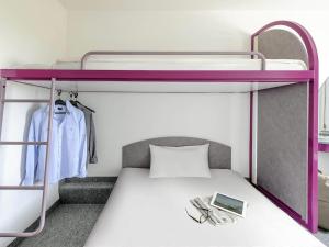 a bedroom with a bunk bed with a purple bunk bed frame at ibis budget Berlin Hoppegarten in Hoppegarten