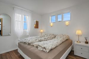 a white bedroom with a bed with a blanket on it at Myrarkot Country Home in Selfoss