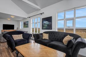 a living room with two black couches and a table at Myrarkot Country Home in Selfoss