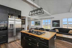 a kitchen with black cabinets and a stainless steel refrigerator at Myrarkot Country Home in Selfoss