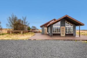 a small house with a wooden porch and a driveway at Myrarkot Country Home in Selfoss