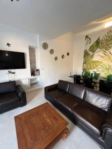 a living room with a leather couch and a table at Villa sedghiani in El Guecheïne