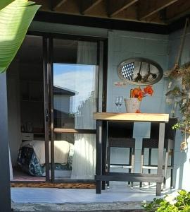 a glass door with a table and a bed at Driftwood Sands Studio in Tairua