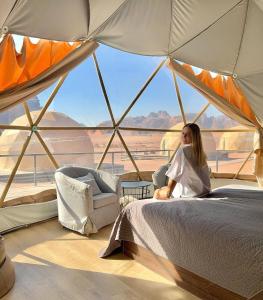 a woman sitting on a bed in a tent at Rum Rhal Luxury Camp in Aqaba