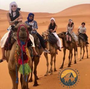 a group of people riding camels in the desert at Rum Rhal Luxury Camp in Aqaba