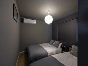a bedroom with two beds and a light fixture at tonaResort Furano in Furano