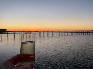 a person holding a glass of wine in front of the water at Sunny Shack in Black Point Landing