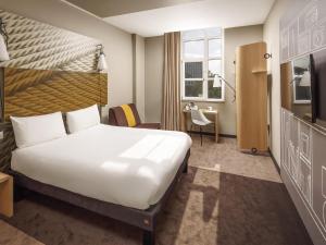 a hotel room with a large bed and a desk at ibis Coventry Centre in Coventry +61 photos