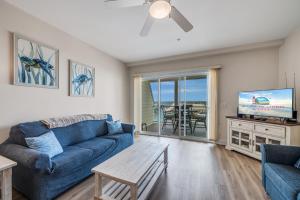 a living room with a blue couch and a tv at Sunset Bay Villa 110 - Hawks Nest in Chincoteague