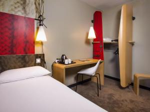 a hotel room with a bed and a desk and a chair at Ibis Sheffield City in Sheffield
