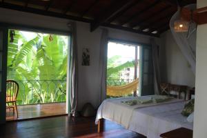 a bedroom with a bed and a large window at Jardim UIXA in Ilha de Boipeba