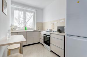 a kitchen with white appliances and a table and a window at Apartament Gdańsk Sun and Sea in Gdańsk