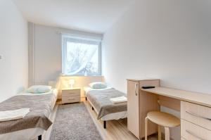 グダニスクにあるApartament Gdańsk Sun and Seaのベッド2台、デスクが備わる小さな客室です。