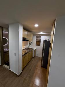 a kitchen with a black refrigerator and wooden cabinets at Fly At Home Bogotá in Bogotá