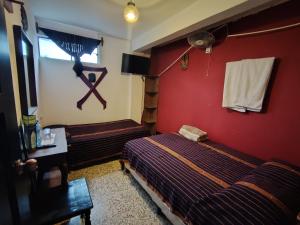 a room with two beds and a red wall at Hotel Sueño Real in Panajachel