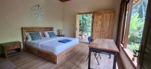 a bedroom with a bed and a table and a window at Praba House in Ubud