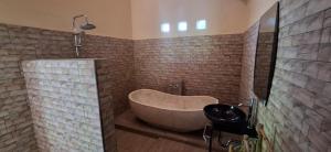 a bathroom with a tub in a room with bricks at Praba House in Ubud