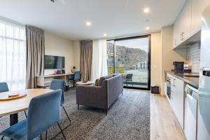 a kitchen and a living room with a table and chairs at Quest Queenstown Apartments Remarkables Park in Queenstown