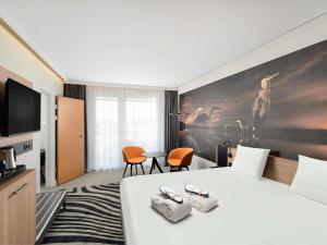 a hotel room with a bed and a tv at Novotel Szeged in Szeged