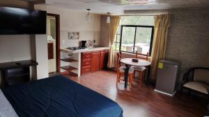 a room with a bed and a kitchen with a table at Casa y Flores in Baños +30 photos