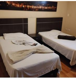 two beds in a room with white sheets at Hotel Platino Plaza in Dosquebradas