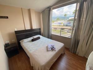 a bedroom with a bed with a towel and a window at Hotel Platino Plaza in Dosquebradas