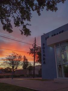 a building with the sunset in the background at Hosteria Posada Drake in Puerto San Julián
