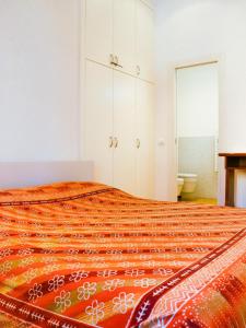 a bedroom with a large bed with an orange blanket at Sanremo Apartments - Orchidea in Sanremo +3 photos