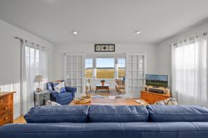 a living room with a blue couch and a tv at To the Lighthouse in Birch Town