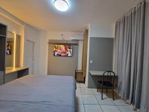 a bedroom with a bed and a tv on the wall at Condomínio Inn Studio in Foz do Iguaçu