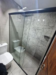 a bathroom with a glass shower with a toilet at Condomínio Inn Studio in Foz do Iguaçu