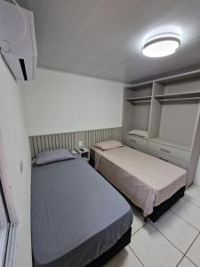 a bedroom with two beds and a light on the ceiling at Condomínio Inn Studio in Foz do Iguaçu