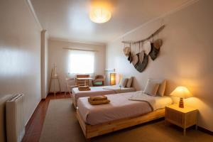 a bedroom with two beds and a chair and a window at BE LOST - Guest House in Pedra Do Ouro