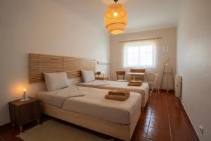 a bedroom with two beds and a table and a window at BE LOST - Guest House in Pedra Do Ouro
