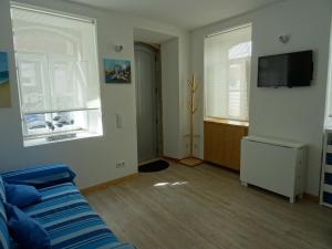 a living room with a blue couch and two windows at Casa do Bairro in Sesimbra