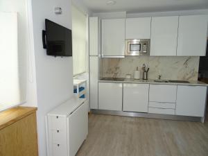 a white kitchen with white cabinets and a sink at Casa do Bairro in Sesimbra