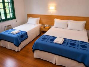 a bedroom with two beds with blue and white sheets at Hotel Internacional São Paulo in São Paulo +18 photos