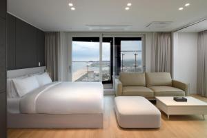 a bedroom with a large white bed and a couch at Emerson Suites Naksan in Yangyang